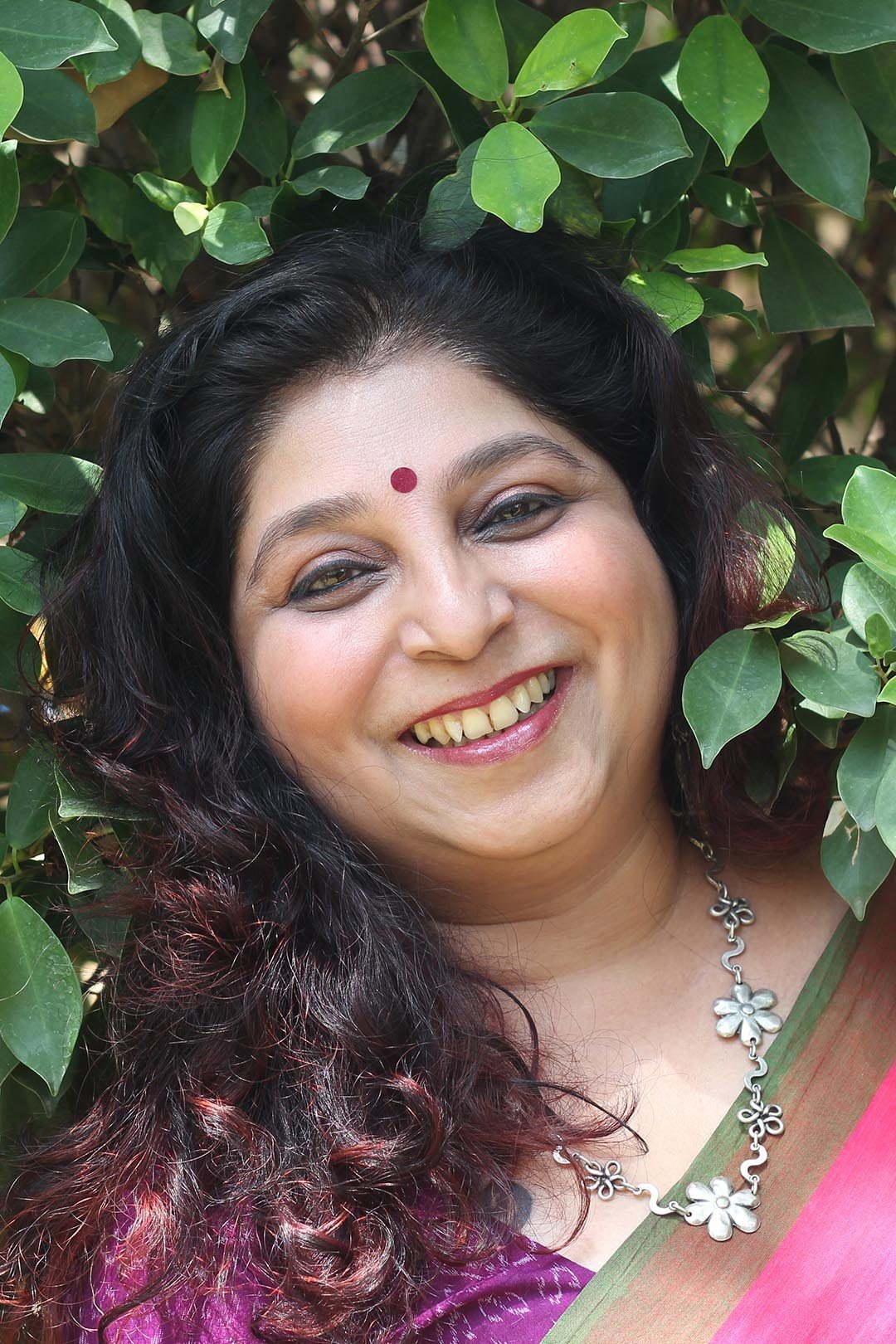 Sameera Kamulkar smiling, hands joined in namaste, in a purple sari